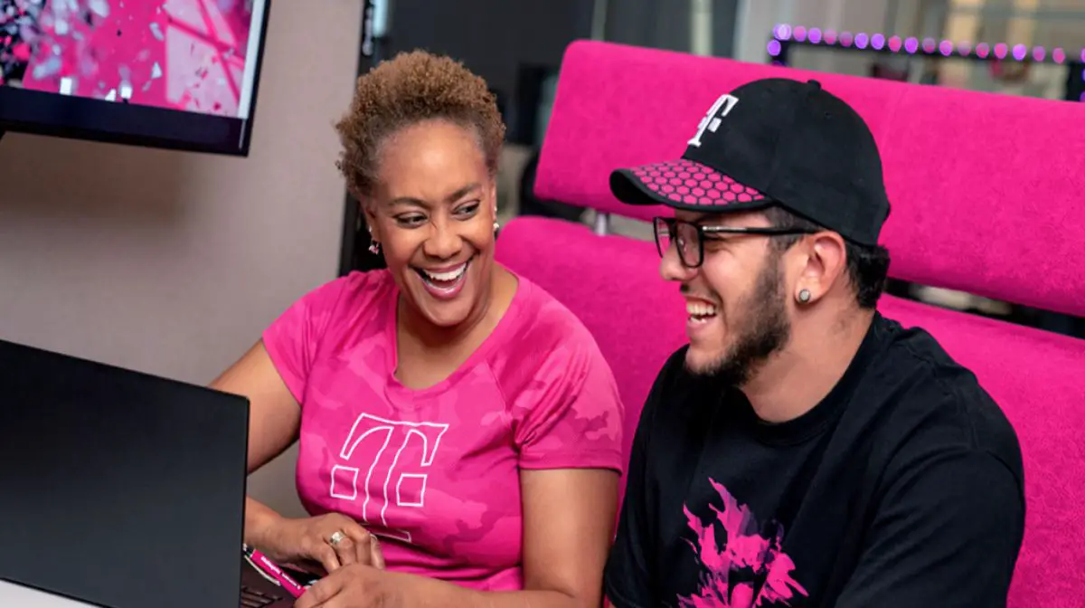 Two T-mobile employees chatting in front of the computer.