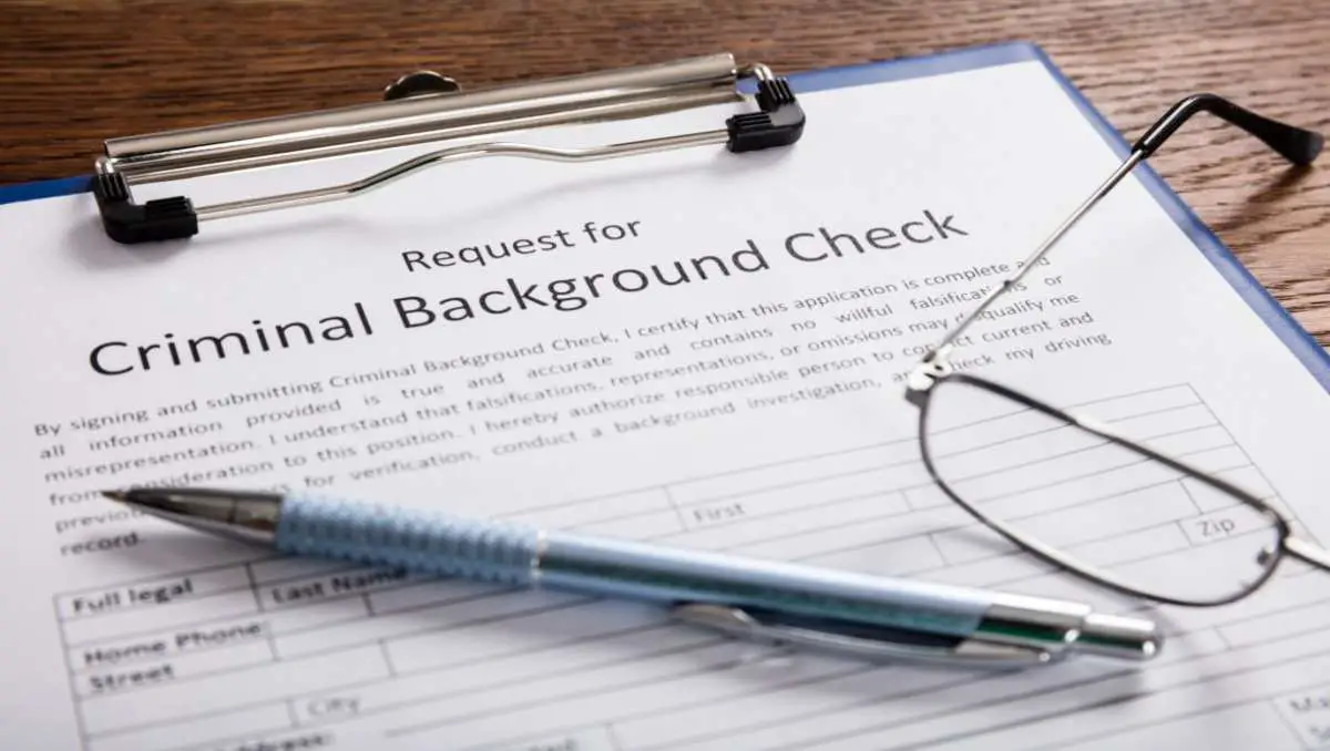 A pen and an eyeglass on top of a Criminal Background Check document. 